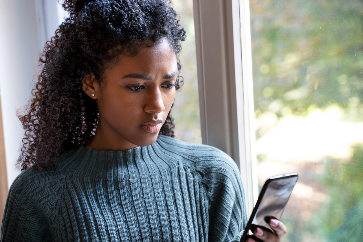 Woman looking at her phone with a concerned look on her face.